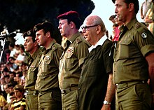 יצחק שפירא (בבגדים אזרחיים) עם הרצל שפיר לשמאלו ומרדכי גור לימינו בטקס סיום מחזור של הפנימייה הצבאית לפיקוד בבית בירם, 1977