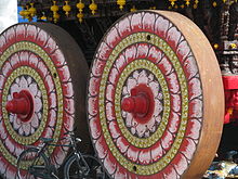 Solid wheels on a heavy temple car, contrasted with the lighter wire-spoked wheels of the black roadster bicycle in the foreground India - Kanchipuram - 023 - chariot unveiled for upcoming festival (2507526057).jpg