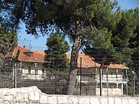 One of the orphanage buildings, behind a high stone wall and protective fencing Schneller Orphanage building.jpg