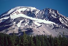 Montagne s'élevant au-dessus d'une forêt de conifères avec un glacier occupant un large cirque sous le sommet.