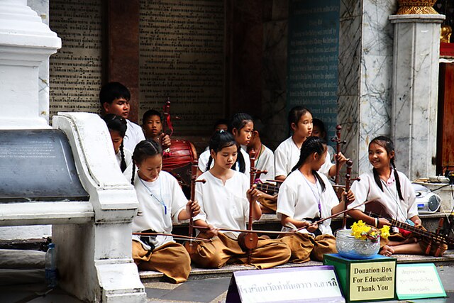 Schoolgirls and boys playing khrueang sai in front of a temple