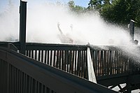 Spectators being hit and soaked in the Splash Zone by a wave created as a boat makes it to the bottom of the drop. Timberwolf Falls Soak Zone CW.jpg