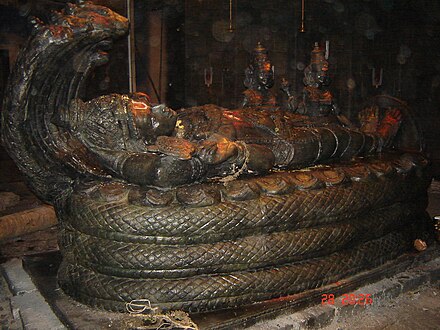 Picture of the film set depicting the Vishnu idol used in the film. The idol, made out of black stone and smeared with kumkuma and sandalwood paste, depicts Vishnu lying on his 7-headed serpent Shesha, attended by Vishnu's consorts Sridevi and Bhudevi at right.
