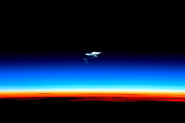 Afterglow of the troposphere (orange), the stratosphere (blue) and the mesosphere (dark) at which atmospheric entry begins, leaving contrails, such as