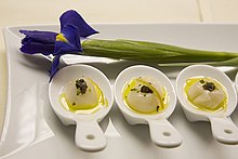 Trois petits plats, avec un iris au-dessus pour la décoration, sur une plus grande assiette rectangulaire