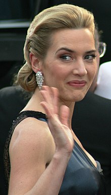 Kate Winslet turned around facing left smiling at the camera and waving