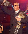 Kurt Angle with the original TNA World Heavyweight Championship title belt design with the IWGP Heavyweight Championship beside it