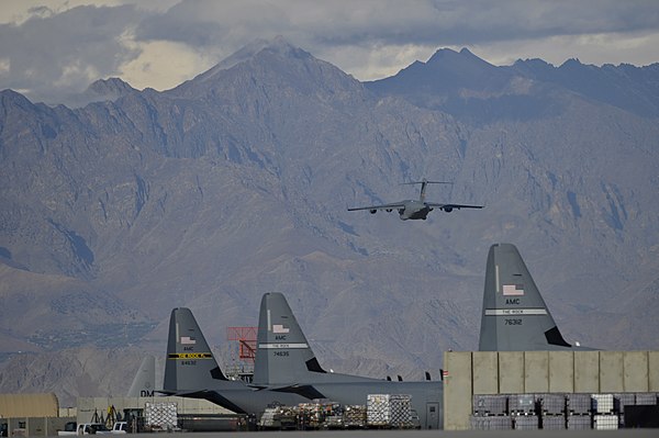 A C-17 Globemaster III takes off from Bagram Airfield near C-130 Hercules deployed with the wing