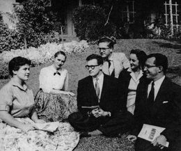 Fotografía en blanco y negro de un grupo de cantantes sentados en un jardín.