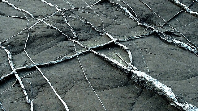 White veins in dark rock at Imperia, Italy