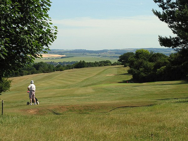 Part of Golf Club course and agricultural and wooded hills with footpaths in background.