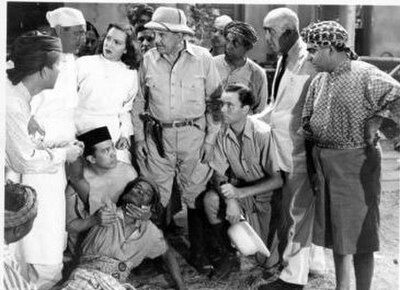 Film still for Tiger Fangs (1943), Frank Buck (centre), June Duprez on Frank Buck's right