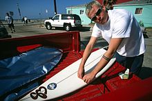 DeLonge with a surfboard in the mid-1990s. The band rose from the southern California skate/surf scene. Tom Delonge with surfboard.jpg