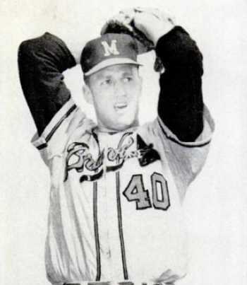 A man wearing a baseball cap with the letter "M" at the centre and white baseball uniform with the words BRAVES and the number 40 across the centre, winds up and prepares to deliver a pitch