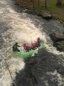 Afon Tryweryn rafters hitting the standing wave of a hydraulic jump.