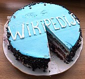 Gâteau au glaçage bleu clair portant l'inscription « Wikipedia » en lettres blanches.