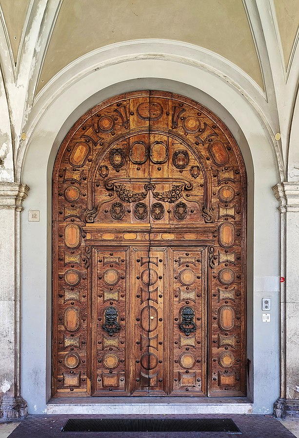 It is a wooden door made by Giorgio Razzani (1631). It was the main entrance to the hospital (Santissimo Crocifisso) built in the mid-15th century in Cesena, at the behest of Malatesta Novello. It was rebuilt in 1776-95 by Agostino Azzolini following the original project. In the mid-19th century the palace was rebuilt again, but the wooden door still stands as a witness superstar.