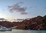 Rocky barren island with some boats in the sea