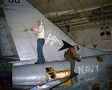 Crewmen service a VA-81 A-7E aboard USS Saratoga in 1986 A-7E VA-81 hangar CV-60 1986.jpeg