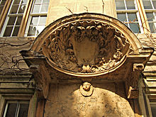 una gran concha con un escudo en el centro y hojas talladas a su alrededor;  la cabeza de un querubín debajo del caparazón
