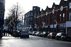 Savile Street in Kingston upon Hull, with Christmas decorations up on streetlight poles contrasting with LGBTQ+ Pride flags of the street's new assortment of gay bars.