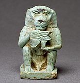 Amuletă care îl înfățișează pe Thot sub formă babuin, ținând un Ochi al lui Horus; 664–332 î.Hr.; faianță egipteană cu glazură verde deschis; înălțime: 3,9 cm, lățime: 2,4 cm, adâncime: 2,5 cm; Muzeul de Artă Walters (Baltimore, SUA)