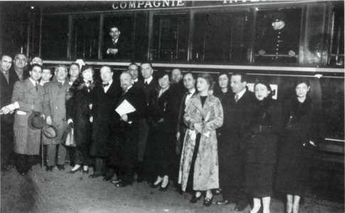 Photographie en noir et blanc d'une vingtaine de personnes posant devant un train de passagers.