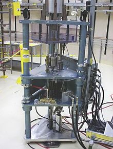 A cylindrical wire cage encloses the spherical uranium mass at the top of this image of Godiva II. Godiva critical mass assembly machine.jpg