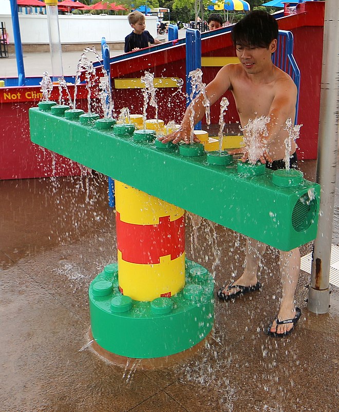 The first feature that users encounter when entering the Legoland Water Park is the Aquatune hydraulophone, an underwater pipe organ.  The hydraulophone is the centerpiece of a series of interactive exhibits on either side of it that teach other elements of flow, such as water tables, and small water laboratory-like spaces where participants can explore hydraulophonic-like action (blocking water jets to create head, pressure, etc.), and also construct dams from Lego bricks.