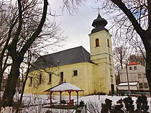 Žlutý kostel s černou střechou a věží