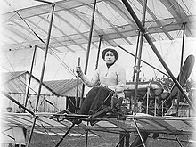 Eine Frau sitzt am Steuer eines frühen Flugzeugs