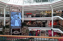 Überblick der zentralen Halle in der Lugner City mit großem Portrait-Foto von Richard Lugner und Hashtag #gemmalugner4ever