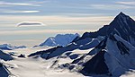 A glacier, mountains of black gravel and snowcovered mountains.