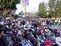The normally massive crowd gathering to watch the 2004 Rose Parade, some pay for seats in stands (far left), others spent the night to "reserve" a free spot, Pasadena