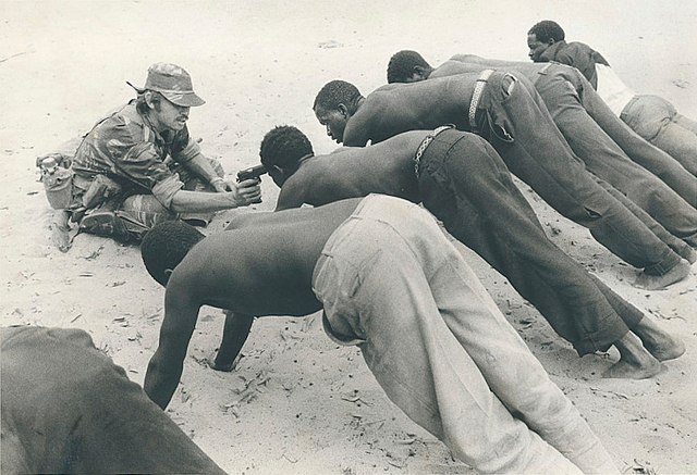 Rhodesian soldier interrogating villagers in late 1977 at gunpoint. This photograph would become one of the most enduring images of the Bush War.