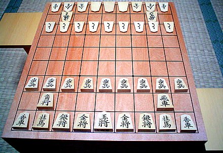 Shogi board with pieces in their starting positions in the front, and promoted pieces in the back