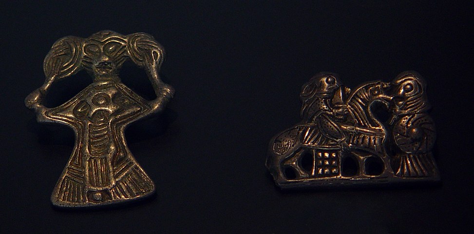 前を向いて髪を触る女性の像（左）と、羽のついた槍を佩き手に剣を持って馬に跨る女性の像（右）
