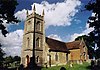 A stone church with a battlemented tower and brick transepts