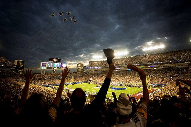 Fans wave as the United States Air Force Thunderbirds fly over the stadium during the pregame ceremony