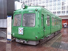 The sectioned body of a former Tokyu 5000 series Green frog carriage on static display in front of the west side of the station