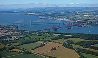 Widok na zatokę Firth of Forth i mosty (od prawej do lewej) Forth Bridge, Forth Road Bridge i Queensferry Crossing; miasto Queensferry po lewej stronie