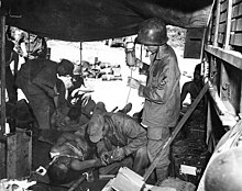 Medics treat a pair of injured men in a tent