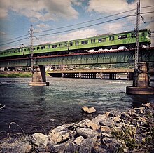JR Nara Line train crossing the Uji River on the rail bridge in Uji, Japan