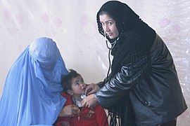 Afghani nurse treating a child with a woman wearing burka