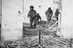 Four men in bombed building walking over rubble