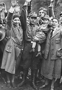 Une dizaine d'hommes et femmes font le salut nazi devant la caméra.