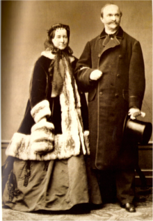 Photographie noir et blanc d'un couple d'une cinquantaine d'année. L'homme porte un veston et la femme un manteau de fourrure.