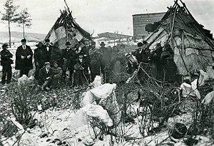 black and white image of two teepees with a dozen or more people, some in suite