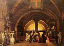 Painting of dozens of men in white robes in a domed chapel. A young man with short black hair and dark blue robe is kneeling on a stool in the center, and pointing at something in a large open book which is being held by one of the white-robed men.