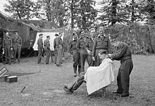 Pilots line up for a haircut while waiting on standby near the No. 122 Wing Operations Room at Martragny, Normandy. In the chair is Flying Officer J. M. W. Lloyd of No. 65 Squadron RAF. Royal Air Force- 2nd Tactical Air Force, 1943-1945. CL550.jpg